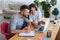 Husband writing in notebook while wife showing something to him