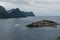 Husoy island at Senja, Norway. Motorboat going around of the island. Mountains on the background.