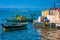 Hut by the seaside. Sunlit small blue, white and yellow Mediterranean fishing boats, with sparkling turquoise sea and pale blue