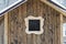 Hut with a wooden window in the wall of raw brown wooden planks with knots. Frontal view. Close-up