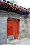 A Hutong House Entrance with Red Gate and Grey Colour Brick Wall