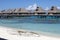 Huts on water in the sea and a small white boat on the shore