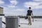 HVAC technician walking up to a condenser on roof