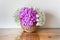 Hydrangea flowers in wicker basket on wooden table covered with glossy glass