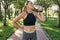 Hydration. Thirsty sporty woman in sportswear drinking water after jogging in a green park on a sunny summer day