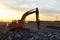 Hydraulic breaker hammer for the destruction of concrete and hard rock at the construction site. Excavator on sunset background.