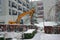 Hydraulic excavator dredger in winter working on a civil engineering construction site in snowy weather .
