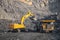 Hydraulic excavator loads coal into body of large yellow mining truck. Open pit mine industry for anthracite