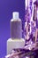 Hydrophilic cleanser oil mockup and holiday tinsel on cube podium on violet background, vertical