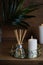 hygge and aromatherapy concept - candles and aroma reed diffuser on table at home
