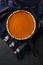 Hygge still life concept. Homemade pumpkin pie in cast iron pan on woolen cloth on black background copy space