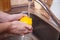 hygiene, health care and safety concept - close up of man hands washing lemon fruit in kitchen at home