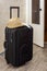 Hygiene mask on a travelerâ€™s hand luggage next to a hat indoors at the door