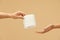 Hygiene. Toilet Paper Roll In Female Hand On Beige Background. One Woman Gives Tissue Paper To Another. Using High-Quality Product