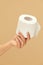 Hygiene. Toilet Paper Roll In Female Hand On Beige Background. Stop Panic About COVID Outbreak