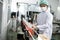 Hygiene worker working in drink factory at conveyor belt with fruit juice glass bottled in production line