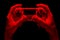 Hyman hands holding white video game gamepad in neon lights isolated on a black