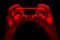 Hyman hands holding white video game gamepad in neon lights isolated on a black