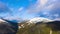 Hyper lapse of clouds running on blue sky over amazing landscape of high snowy mountains and coniferous forest on the