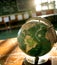 A hyperrealistic close-up of a world globe on a classroom desk