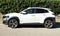 Hyundai Kona X parked at the roadside. Side view with a hedge on background