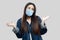 I don`t know. Confused beautiful brunette asian young woman with surgical medical mask in blue denim jacket standing raised arms