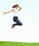 I feel great. Young woman leaping with joy while holding on to her hat.