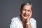 I have so many good stories to tell. Studio shot of a senior woman posing against a grey background.