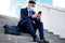 I hope to hear from you soon. Shot of a young businessman sitting on steps using his smartphone.