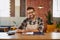 I keep my business running smoothly. Portrait of a happy young business owner doing admin at a table in his coffee shop.