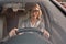 I love driving my car. Portrait of attractive young business woman in eyeglasses smiling while driving a car