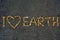 I love Earth, symbolic message for global change and protecting environment. Tiny stones make a writing on a black sand background