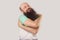 I love myself. Portrait of happy middle aged bald man with long beard in light green t-shirt standing hugging himself smiling and