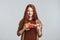 I love surprises Cute and happy redhead woman opening gift box while standing against grey background