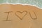 I Love You drawn on sandy beach with wave approaching
