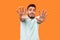 I`m afraid! Portrait of scared terrified brunette man making frightened gesture with raised hands. isolated on orange background