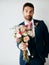 I picked these especially for you. Studio shot of a handsome young groom holding a bunch of flowers a gray background.