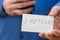 I Refugee. Inscription in jagged gray letters on paper. Man holding up two white paper rectangles with handwritten text. Close-up