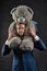 I am so sorry. Man carries giant teddy bear on neck, dark background. Reunion gift concept. Guy calm bearded face with