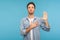 I swear! Portrait of honest responsible man in worker denim shirt giving evidence with raised hand, blue background