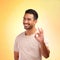 I think youre doing great. a young man showing the ok sign while standing against a yellow background.