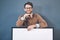 I totally back your brand. Studio portrait of a young man holding a blank sign against a grey background.