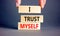 I trust myself symbol. Concept words I trust myself on wooden blocks. Businessman hand. Beautiful grey table grey background.