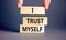 I trust myself symbol. Concept words I trust myself on wooden blocks. Businessman hand. Beautiful grey table grey background.