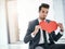 I wouldnt mind a little office romance. Portrait of a trendy young businessman posing with a paper heart in the office.