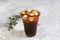 Ice black brew coffee with milk in tall glass with pieces of ice on a grey dark background, natural light, fresh summer drink