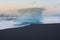 Ice breaking from iceberg on black sand beach