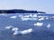 Ice chunks floating in the sea with tall cliffs on the horizon