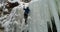 Ice climber climbing frozen cliff during winter 4k