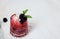 Ice cocktail with fresh mint and blackberries in a pink glass on a white background, white smooth tablecloth. Summer